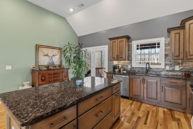 kitchen featuring a kitchen island, lofted ceiling, sink, stainless steel dishwasher, and light hardwood / wood-style flooring