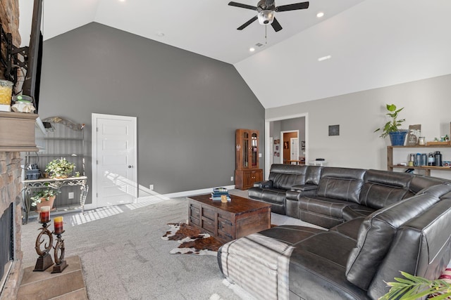 living room featuring a stone fireplace, high vaulted ceiling, light colored carpet, and ceiling fan