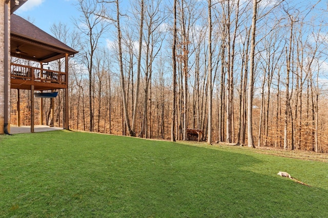 view of yard with ceiling fan and a deck