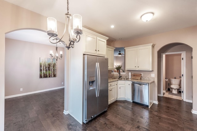 kitchen featuring light stone counters, stainless steel appliances, decorative light fixtures, and sink