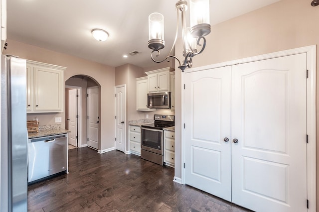 kitchen with pendant lighting, white cabinetry, dark hardwood / wood-style flooring, light stone counters, and stainless steel appliances