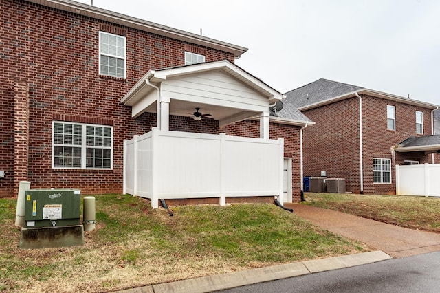 back of property featuring cooling unit, ceiling fan, and a yard