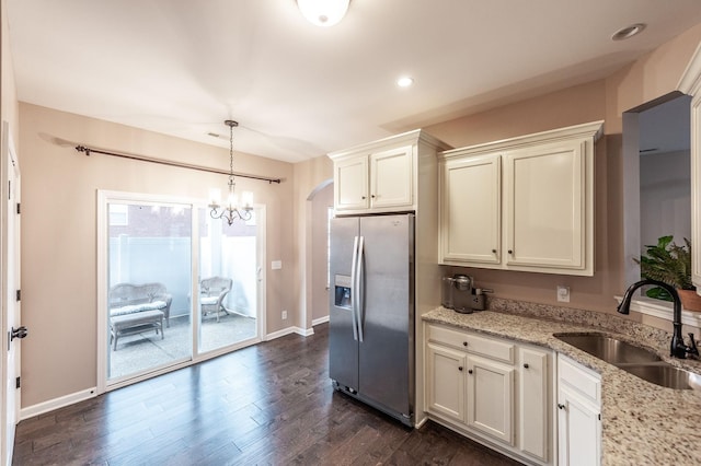 kitchen featuring dark hardwood / wood-style floors, pendant lighting, sink, stainless steel fridge with ice dispenser, and light stone countertops