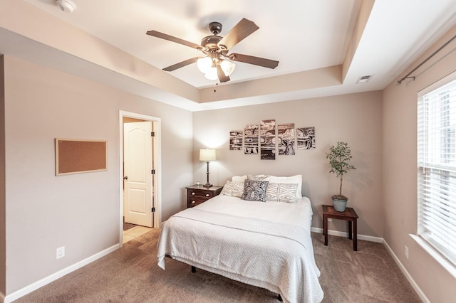 bedroom with a raised ceiling, carpet floors, and ceiling fan