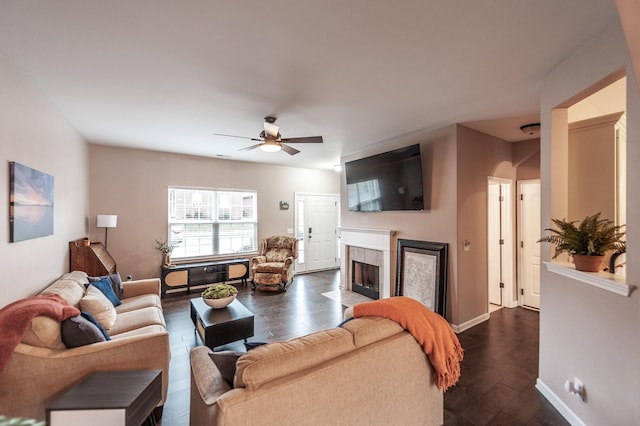 living room with ceiling fan, dark hardwood / wood-style floors, and a tiled fireplace