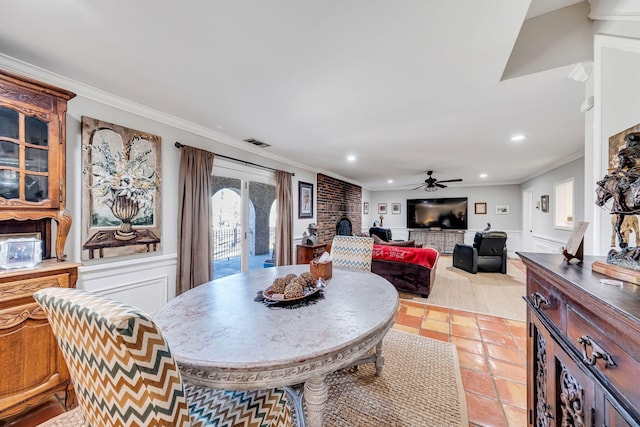 tiled dining room with crown molding, a brick fireplace, and ceiling fan