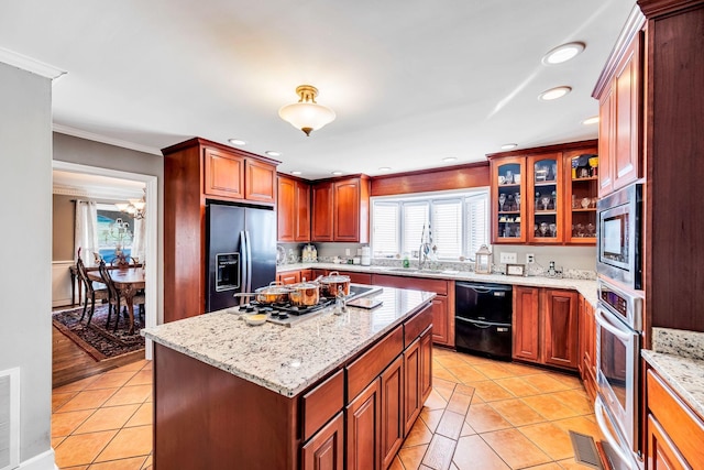 kitchen with a center island, light tile patterned floors, stainless steel appliances, crown molding, and light stone countertops