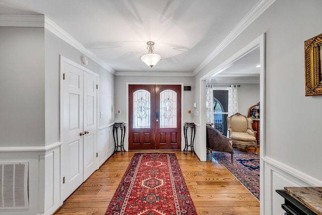 foyer with french doors, ornamental molding, and light hardwood / wood-style flooring