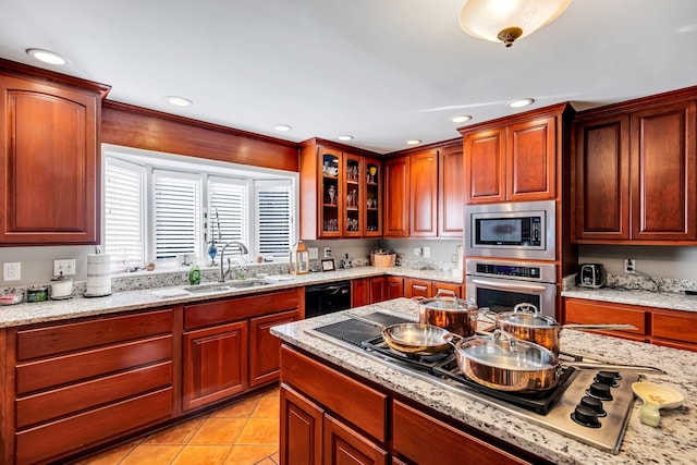 kitchen with sink, light tile patterned flooring, light stone countertops, and appliances with stainless steel finishes