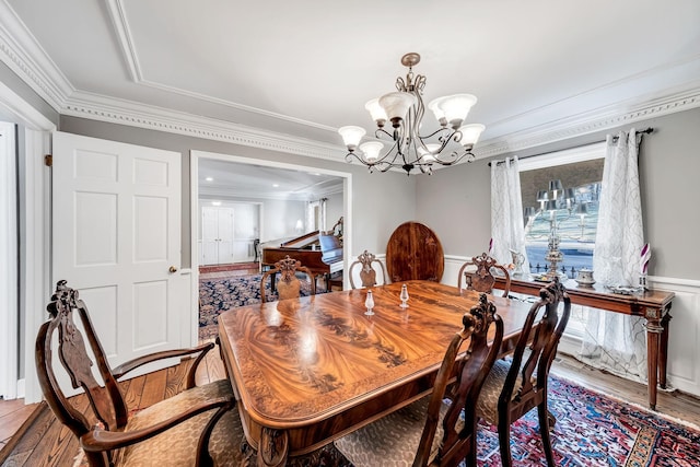 dining area with wood-type flooring, crown molding, and a chandelier