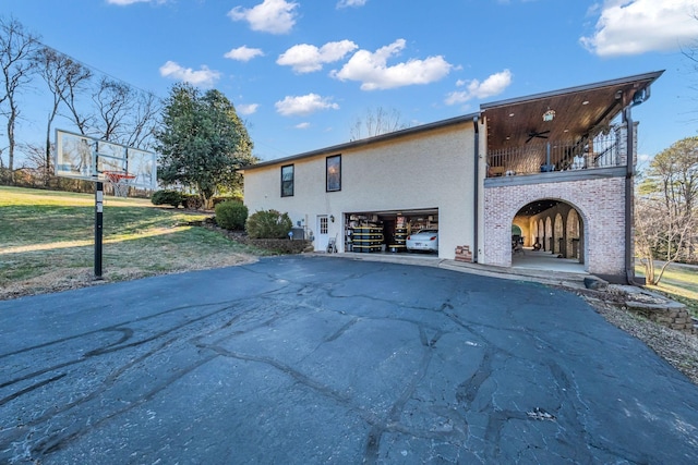 view of property exterior with ceiling fan, a balcony, and a lawn