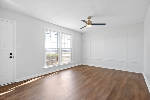 empty room with dark wood-type flooring, a textured ceiling, and ceiling fan