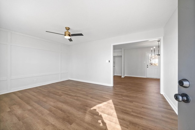 spare room with ceiling fan with notable chandelier and dark hardwood / wood-style flooring