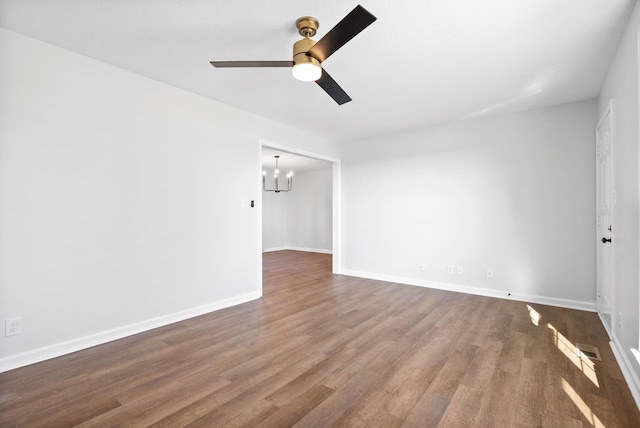 spare room with dark hardwood / wood-style flooring and ceiling fan with notable chandelier