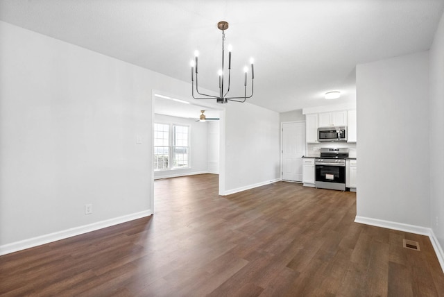 interior space with dark wood-type flooring and ceiling fan with notable chandelier