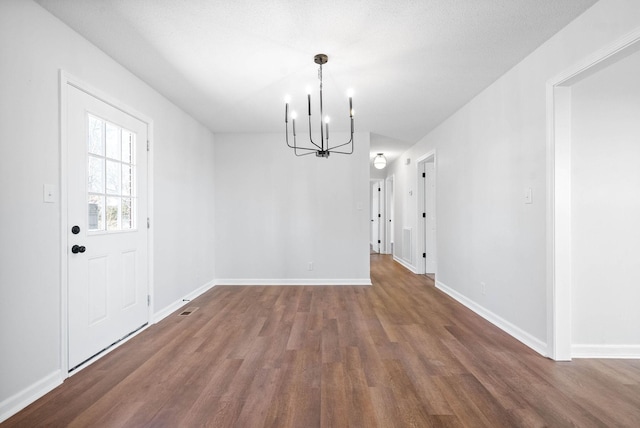 unfurnished dining area with a notable chandelier and dark hardwood / wood-style floors