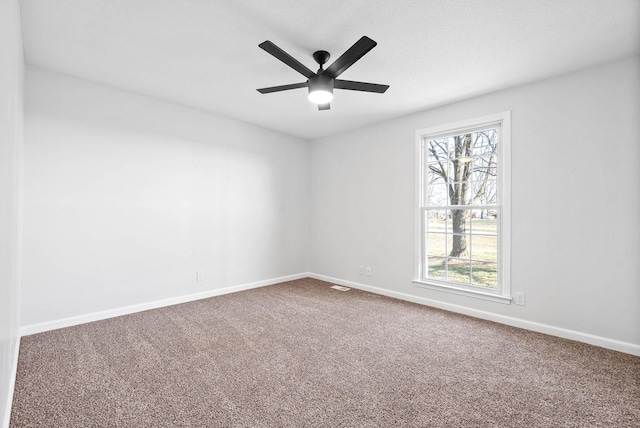 carpeted spare room featuring plenty of natural light and ceiling fan