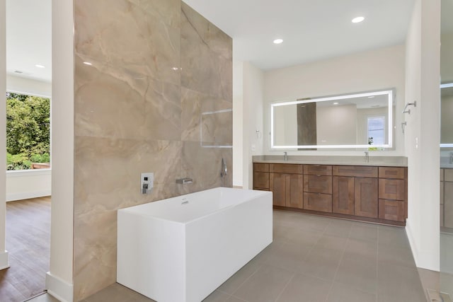 bathroom featuring vanity, tile walls, tile patterned floors, and a tub to relax in