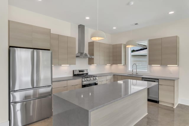 kitchen with wall chimney exhaust hood, sink, decorative light fixtures, appliances with stainless steel finishes, and a kitchen island