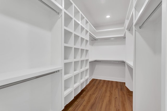 walk in closet featuring built in desk and hardwood / wood-style floors