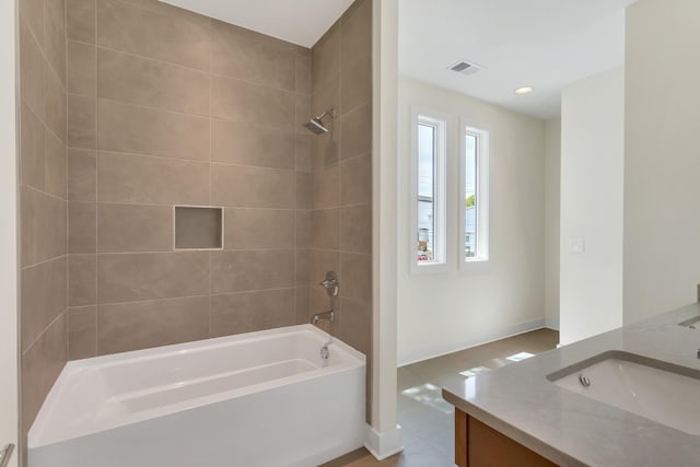 bathroom featuring vanity and tiled shower / bath