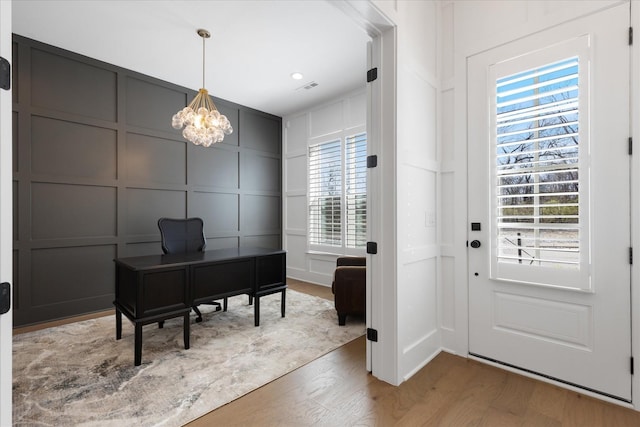 office area with wood-type flooring and a notable chandelier