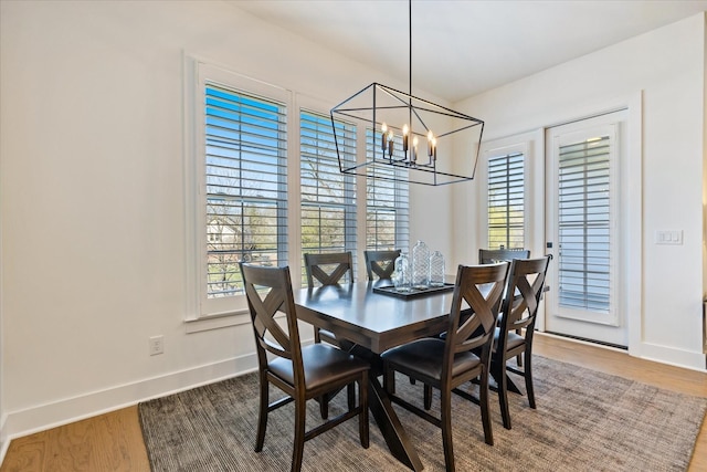 dining space featuring a healthy amount of sunlight, hardwood / wood-style floors, and a notable chandelier