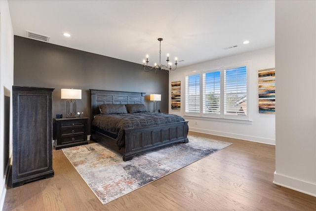 bedroom with an inviting chandelier and hardwood / wood-style floors