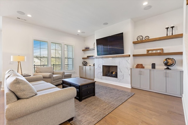 living room with a fireplace and light wood-type flooring