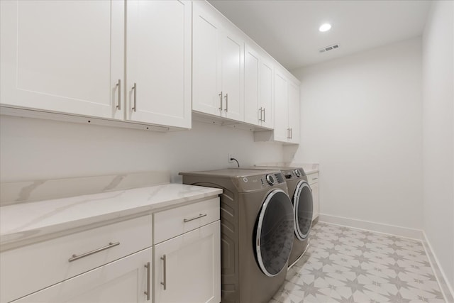 clothes washing area with cabinets and washing machine and dryer