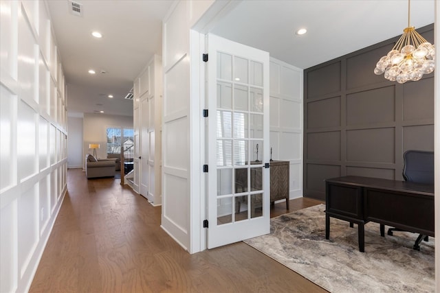 home office with hardwood / wood-style floors, an inviting chandelier, and french doors