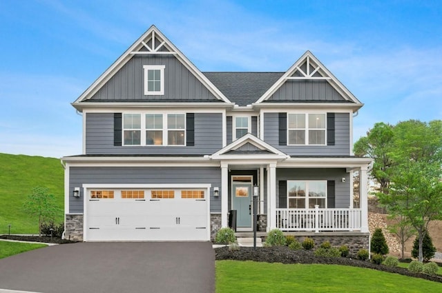 craftsman-style home featuring a garage, a front lawn, and covered porch