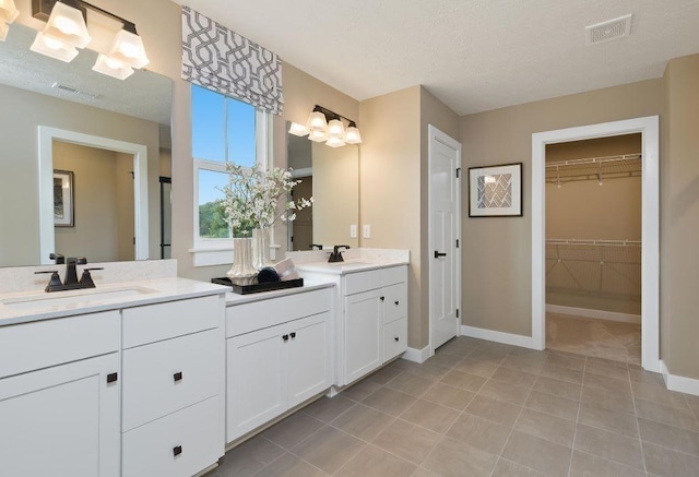 bathroom with vanity, tile patterned flooring, and a textured ceiling