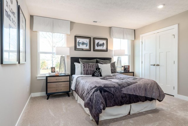 carpeted bedroom featuring multiple windows, a textured ceiling, and a closet