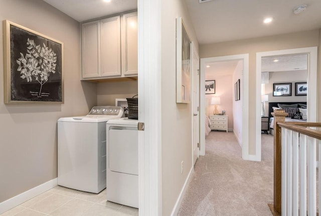 laundry room featuring light tile patterned flooring, cabinets, and washing machine and dryer