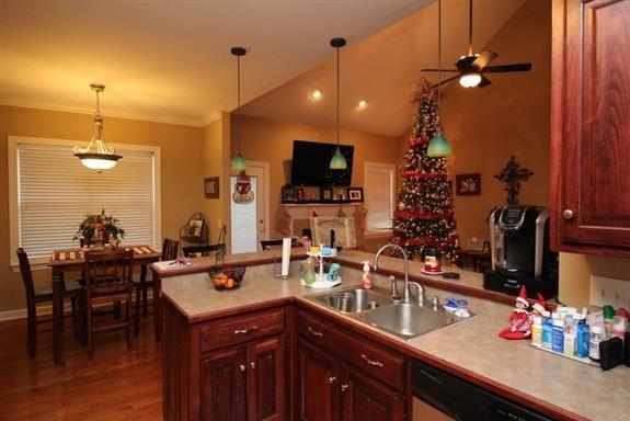 kitchen with lofted ceiling, sink, hanging light fixtures, wood-type flooring, and ornamental molding