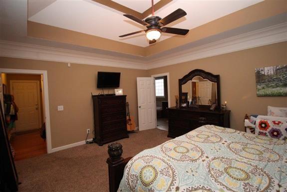 bedroom with ornamental molding, carpet, ceiling fan, and a tray ceiling