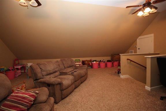 carpeted home theater with lofted ceiling and ceiling fan