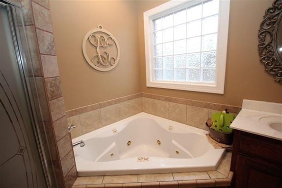 bathroom featuring tiled tub and vanity