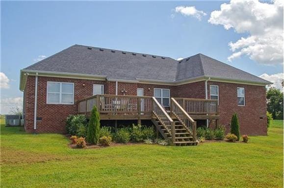 rear view of house with a wooden deck and a yard