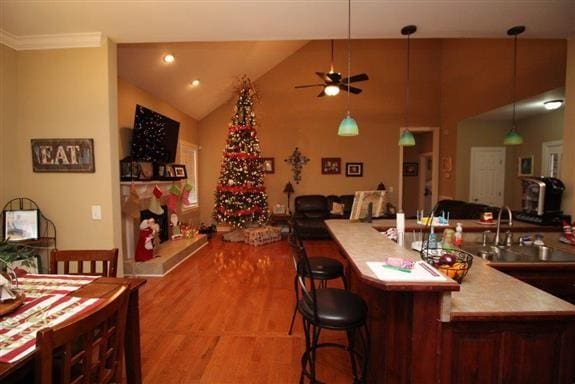 kitchen featuring vaulted ceiling, sink, a kitchen bar, hanging light fixtures, and light hardwood / wood-style flooring