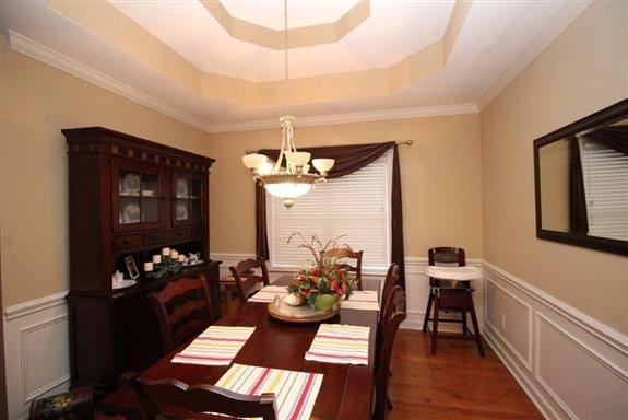 dining space featuring an inviting chandelier, dark wood-type flooring, and a raised ceiling