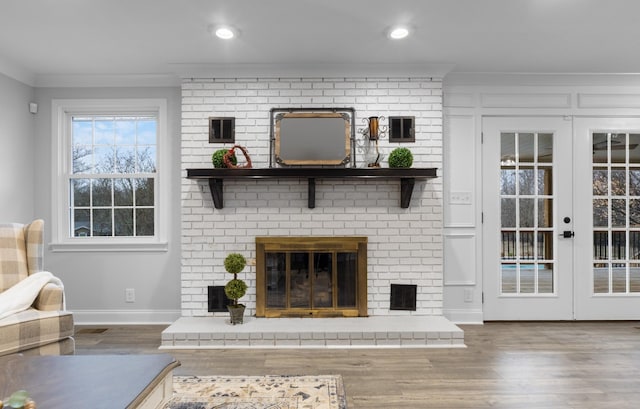 unfurnished living room with a brick fireplace, crown molding, french doors, and hardwood / wood-style flooring