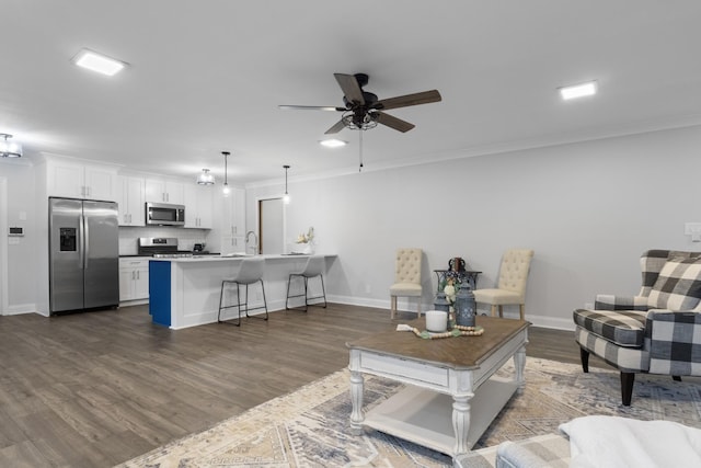 living room with sink, crown molding, dark wood-type flooring, and ceiling fan