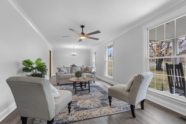 living room with crown molding, ceiling fan, a healthy amount of sunlight, and dark hardwood / wood-style floors