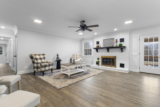 living room with dark hardwood / wood-style flooring, crown molding, a fireplace, and a healthy amount of sunlight