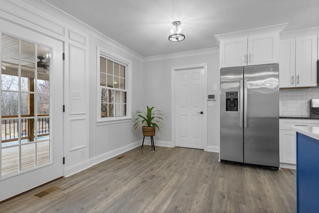 kitchen with white cabinetry, crown molding, wood-type flooring, tasteful backsplash, and stainless steel fridge with ice dispenser