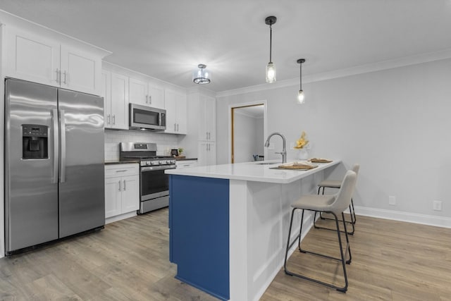 kitchen featuring sink, white cabinetry, hanging light fixtures, stainless steel appliances, and decorative backsplash