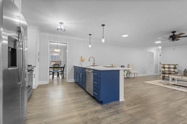 kitchen featuring sink, blue cabinetry, stainless steel appliances, decorative light fixtures, and light wood-type flooring