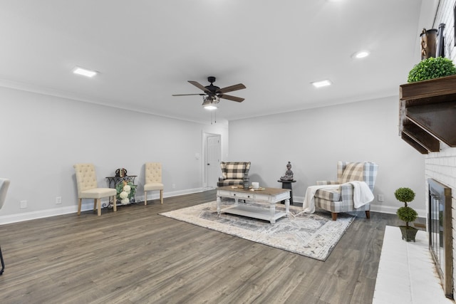 living area with crown molding, a fireplace, dark hardwood / wood-style flooring, and ceiling fan